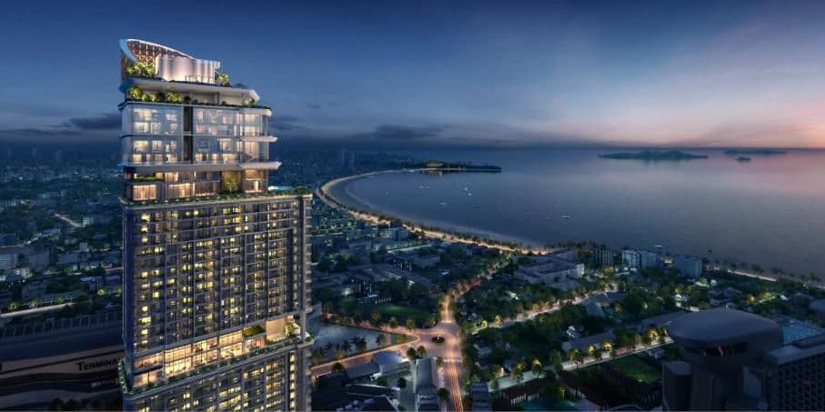 Gratte-ciel moderne illuminé surplombant une baie et une ville au crépuscule, avec jardins suspendus et vue sur mer.
