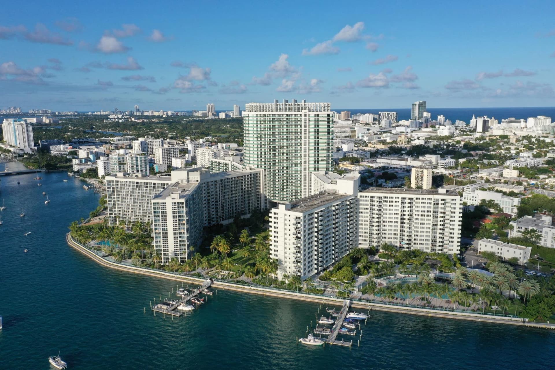 Vue aérienne d'immeubles résidentiels et condos de luxe surplombant une baie avec des quais et bateaux.