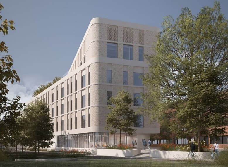 Un bâtiment moderne en briques claires aux angles arrondis, entouré d'arbres et de grandes fenêtres.