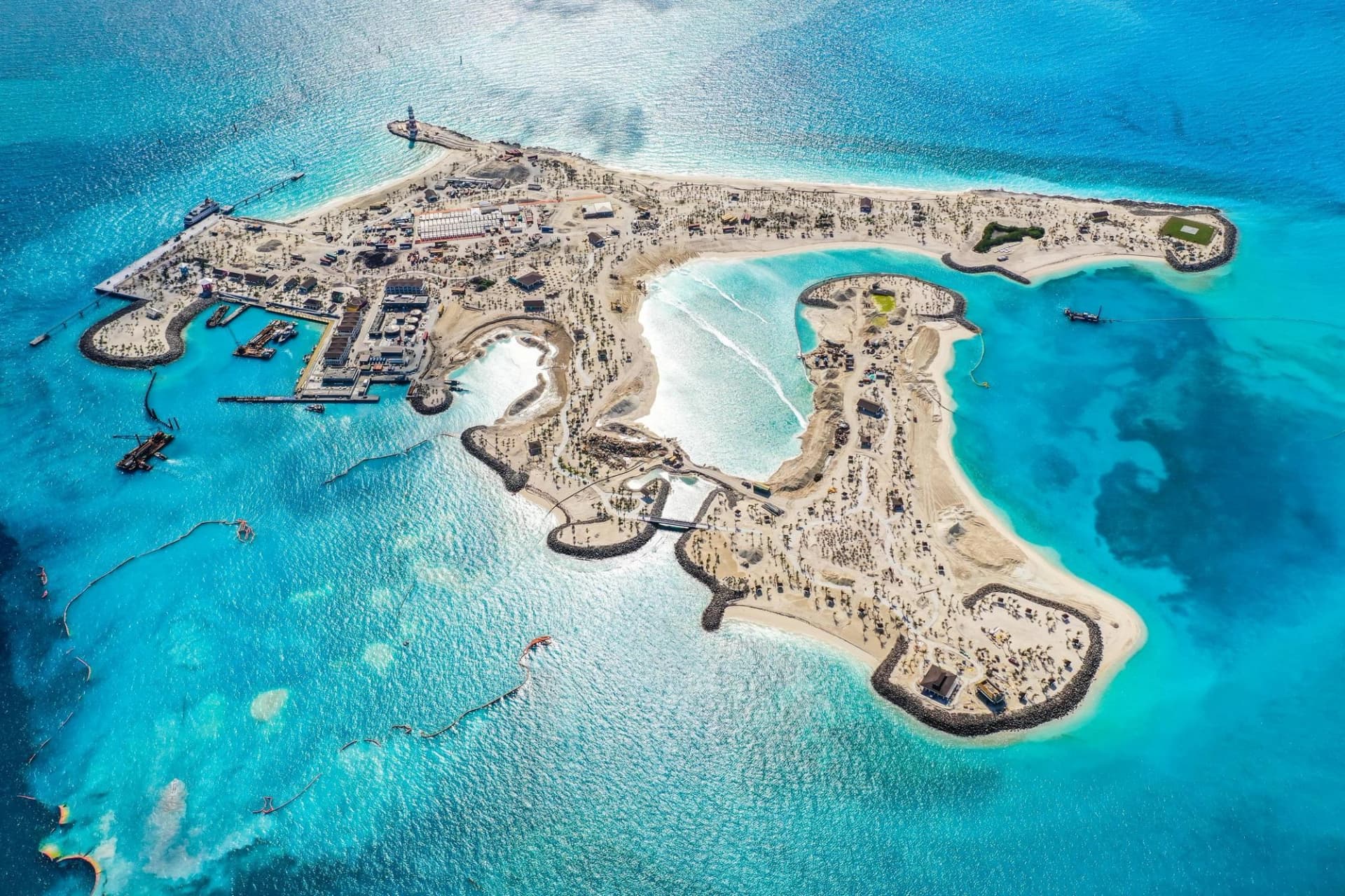 Vue aérienne d'une île tropicale en construction aux Bahamas, entourée d'eaux turquoise cristallines.